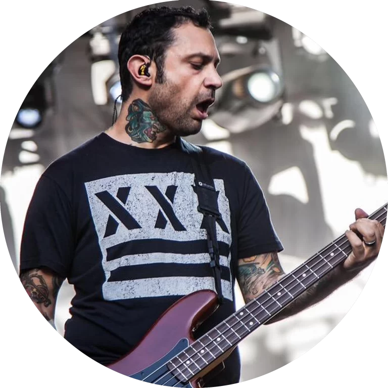 Joe Principe from the band Rise Against wearing an Underground Faction t-shirt with the design Out of Step on the front while playing bass and singing on stage.